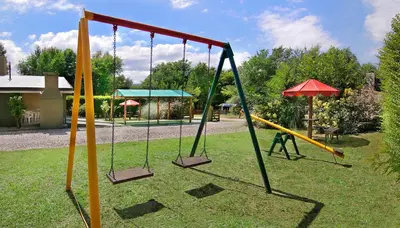two swings in a park with a playground at Cabañas Dolce Vita II in Los Reartes