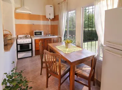 a kitchen with a wooden table with chairs and a stove at Cabañas Dolce Vita II in Los Reartes