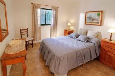 a bedroom with a bed and a table and a window at Cabañas Dolce Vita II in Los Reartes