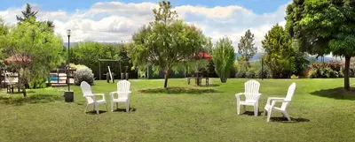 a group of white chairs sitting in a park at Cabañas Dolce Vita I in Los Reartes