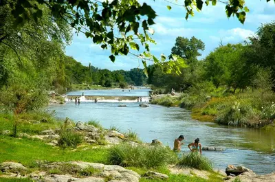 a river with people playing in the water at Cabañas Dolce Vita I in Los Reartes
