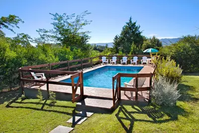 a swimming pool with a deck and chairs around it at Cabañas Dolce Vita I in Los Reartes