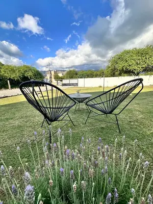 two metal chairs in a field with flowers at Villa Bonita Cabañas Villa de Merlo in Merlo