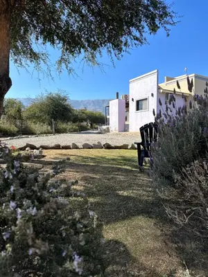 a park bench sitting in the grass near a building at Villa Bonita Cabañas Villa de Merlo in Merlo