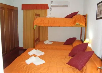 two beds in a room with orange sheets at Hosteria Renca in Renca