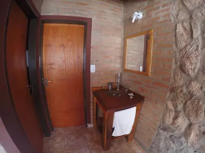 a bathroom with a wooden sink and a brick wall at Aldea Serrana in Nono