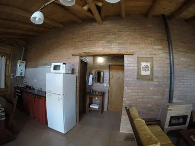 a kitchen with a white refrigerator and a brick wall at Aldea Serrana in Nono