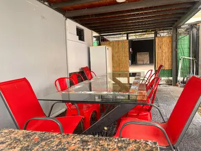 a glass table and red chairs on a patio at ViviSierras, Carlos Paz casa centro frente al lago, pileta climatizada, 4 dormitorios, 3 baños, quincho in Villa Carlos Paz