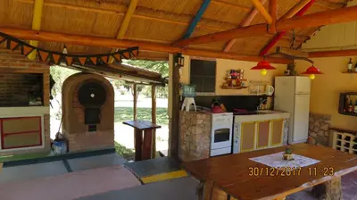 an outdoor kitchen with a table and an oven at Cabañas Entre Verde in Los Hornillos