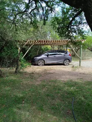 a car parked under a wooden pergola at Cabañas Entre Verde in Los Hornillos