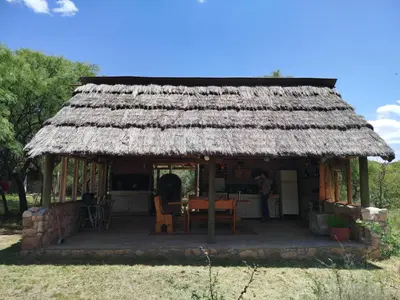 a small hut with a thatched roof with a table at Cabañas Entre Verde in Los Hornillos