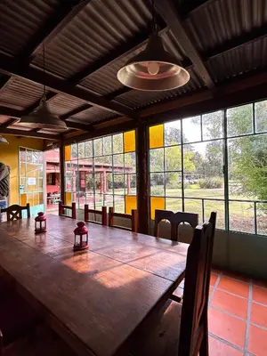 a large wooden table in a room with windows at Posada Buen Camino in Nono