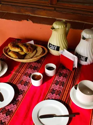 a table with a plate of food and cups of coffee at Posada Buen Camino in Nono