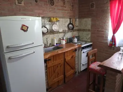 a kitchen with a white refrigerator and a sink at Cabañas Terra Natura in Bialet Massé