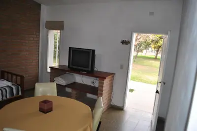 a room with a table and a television and a door at El Chinchero Departamentos in Merlo