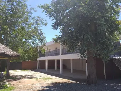 a white building with a tree in front of it at Abuela Mari Apart Cabaña in Villa Cura Brochero