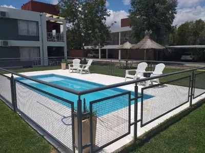 a swimming pool with a fence and chairs around it at Abuela Mari Apart Cabaña in Villa Cura Brochero