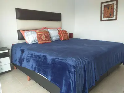 a bed with a blue blanket on top of it at Abuela Mari Apart Cabaña in Villa Cura Brochero