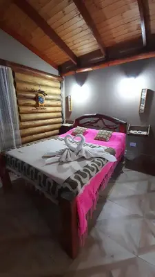 a bedroom with a bed with a pink blanket at Hotel y Cabañas Green Park in Nono