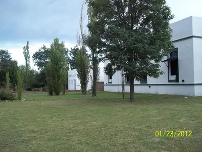 a white house with trees in front of it at Hotel y Cabañas Green Park in Nono