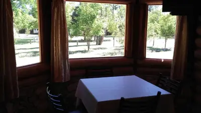 a table and chairs in a room with windows at Hotel y Cabañas Green Park in Nono