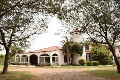 a large white house with trees in front of it at Estancia Santa Leocadia in Bialet Massé