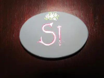 a white plate with the letter s on it at La Posada de Akasha in Villa General Belgrano