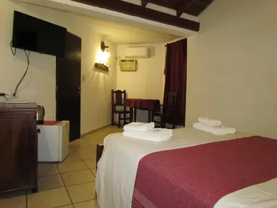 a hotel room with two beds and a flat screen tv at La Posada de Akasha in Villa General Belgrano