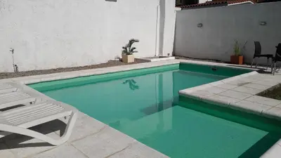 a swimming pool with a chair and a table and a chair at Casa Fleming in Villa Carlos Paz