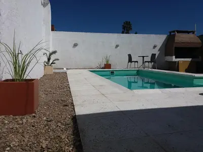 a swimming pool next to a house with a table and chairs at Casa Fleming in Villa Carlos Paz