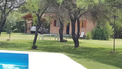 a house with a table and trees in a yard at Cabañas Tia Elmira in Villa Cura Brochero