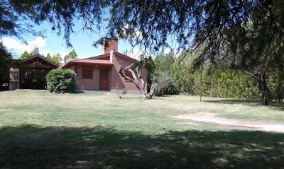 a brick house with a chimney on top of a yard at Cabañas Tia Elmira in Villa Cura Brochero