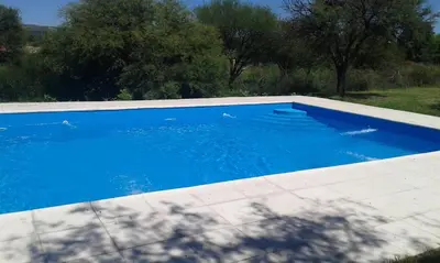 a large blue swimming pool in a yard at Cabañas Tia Elmira in Villa Cura Brochero
