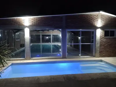 a swimming pool in front of a house at night at Complejo Los Gringos in Villa Ciudad de America
