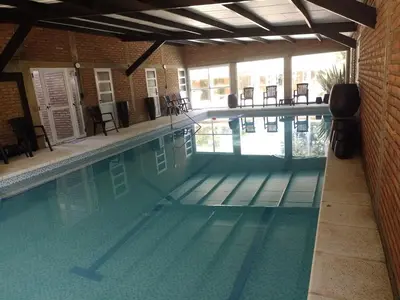a large swimming pool with chairs in a building at Complejo Los Gringos in Villa Ciudad de America