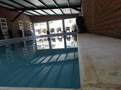an empty swimming pool with chairs and a brick wall at Complejo Los Gringos in Villa Ciudad de America