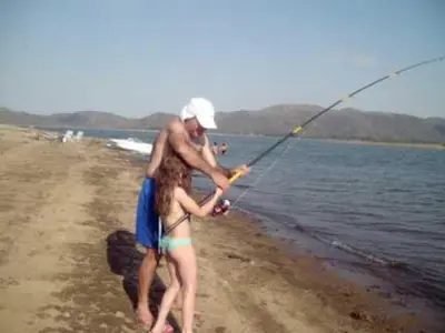 a man and a girl on the beach fishing at Complejo Los Gringos in Villa Ciudad de America
