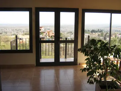 a room with large glass doors and a plant at Balcon de los Molles in Santa Rosa de Calamuchita