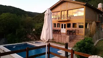 an umbrella in front of a house with a pool at Balcon de los Molles in Santa Rosa de Calamuchita