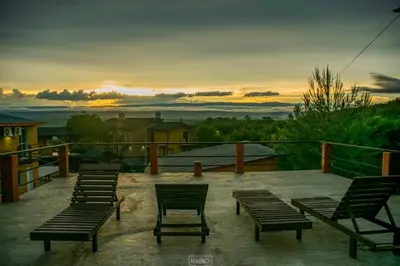 a group of benches sitting on a patio with a sunset at Balcon de los Molles in Santa Rosa de Calamuchita