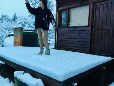 a woman standing on a porch in the snow at Cielo de Piedra. Cabañas y Petit Hotel in Tanti