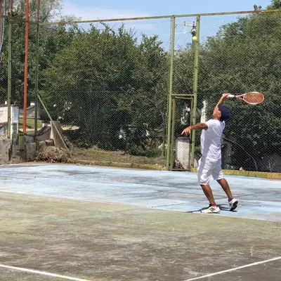 a man hitting a tennis ball with a racket at Cielo de Piedra. Cabañas y Petit Hotel in Tanti