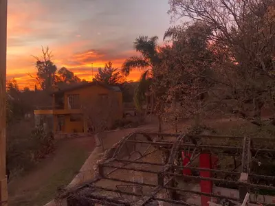a view of a house with a sunset in the background at Cielo de Piedra. Cabañas y Petit Hotel in Tanti