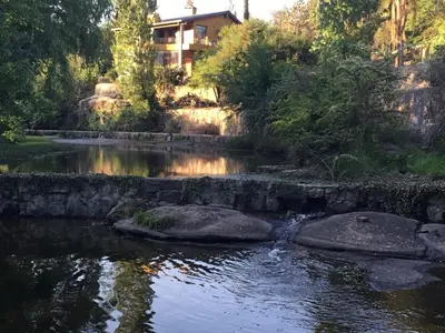 a river with a house in the background at Cielo de Piedra. Cabañas y Petit Hotel in Tanti