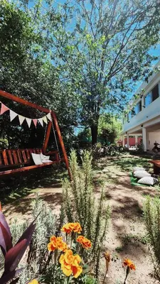 a yard with a swing and flowers and a building at Posada Piedramora in Mina Clavero