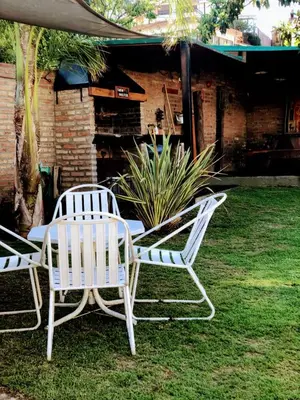 two white chairs and a table in a yard at complejo Casa Walter in Villa Carlos Paz