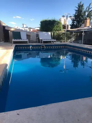 a swimming pool with blue water and white chairs at complejo Casa Walter in Villa Carlos Paz