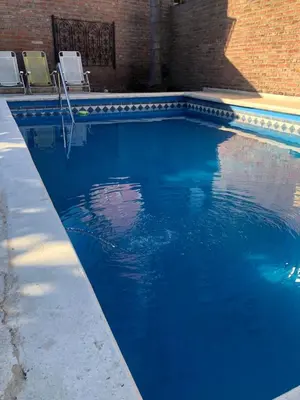 a swimming pool with two chairs and blue water at complejo Casa Walter in Villa Carlos Paz