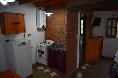 a kitchen with a stove and a brick wall at Cabañas La Rosada in Santa Rosa de Calamuchita