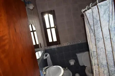 a bathroom with a sink and a toilet and two windows at Cabañas La Rosada in Santa Rosa de Calamuchita